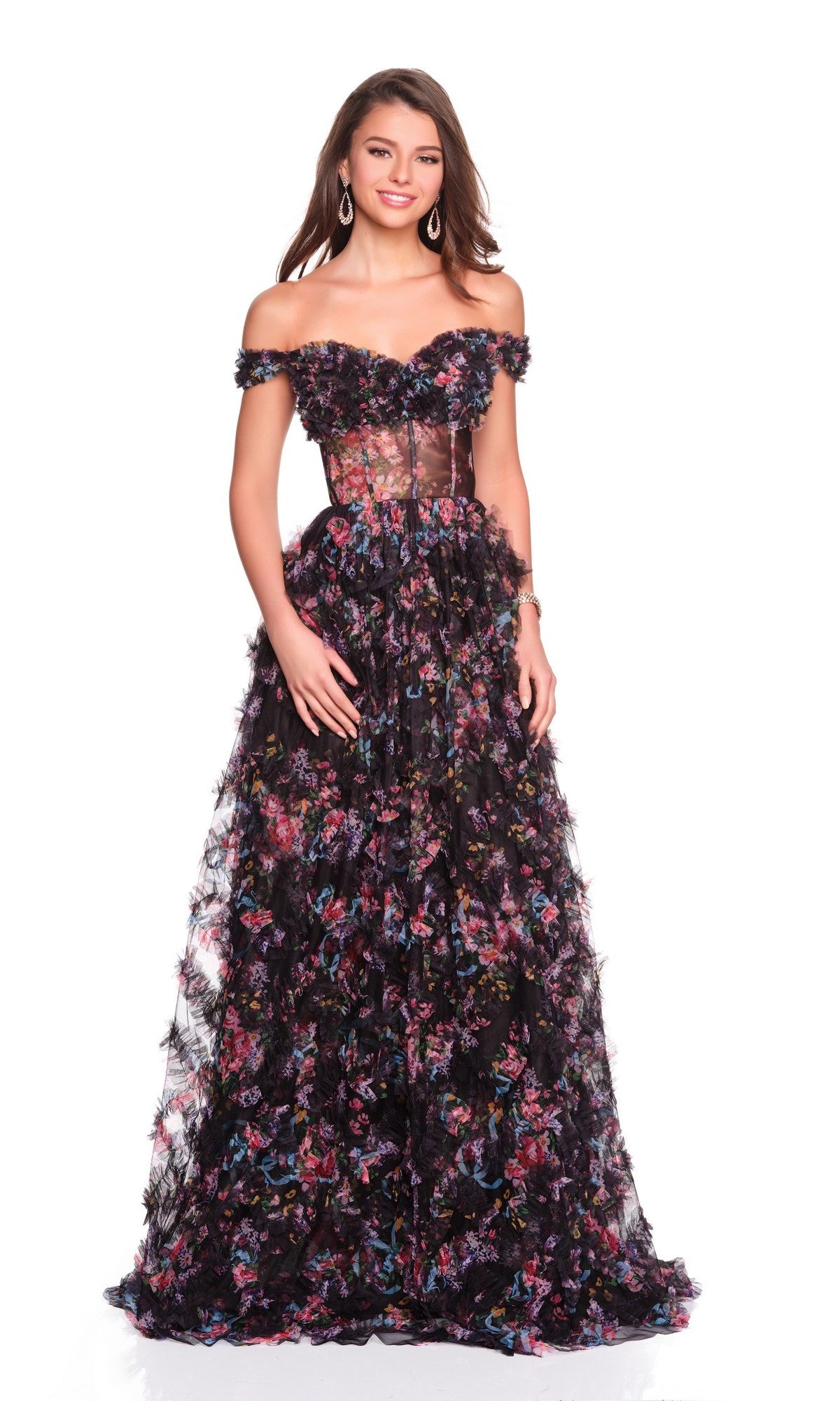 A woman poses against a white background wearing the Dave and Johnny 12508, a black off-the-shoulder long prom dress with a sheer bodice and colorful floral patterns.